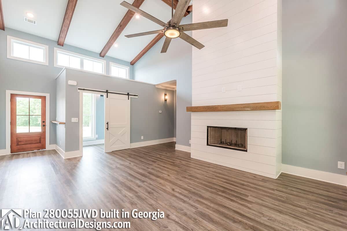 Great room with a large fireplace and a vaulted ceiling lined with exposed beams.