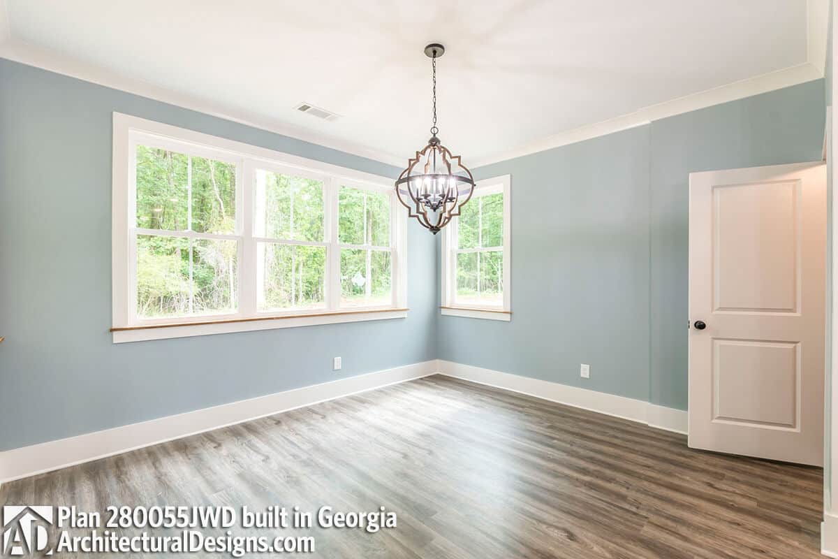 Dining room with hardwood flooring and white-framed windows overlooking the backyard.