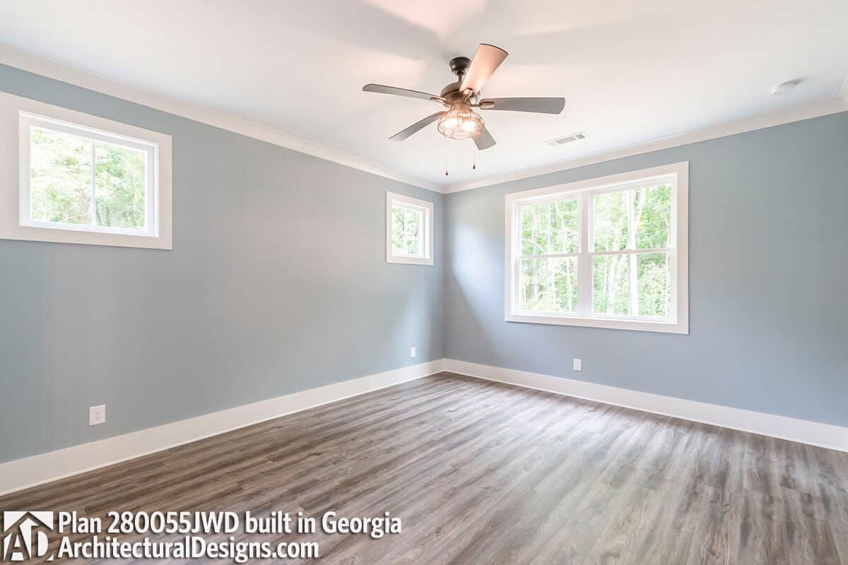 Primary bedroom with hardwood flooring and large windows that bring natural light in.