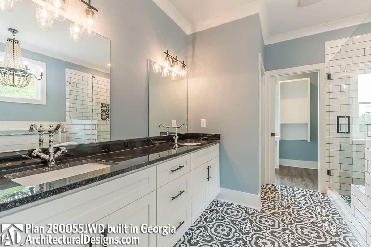 Primary vanity with double sinks and white cabinets over the decorative tiled flooring.