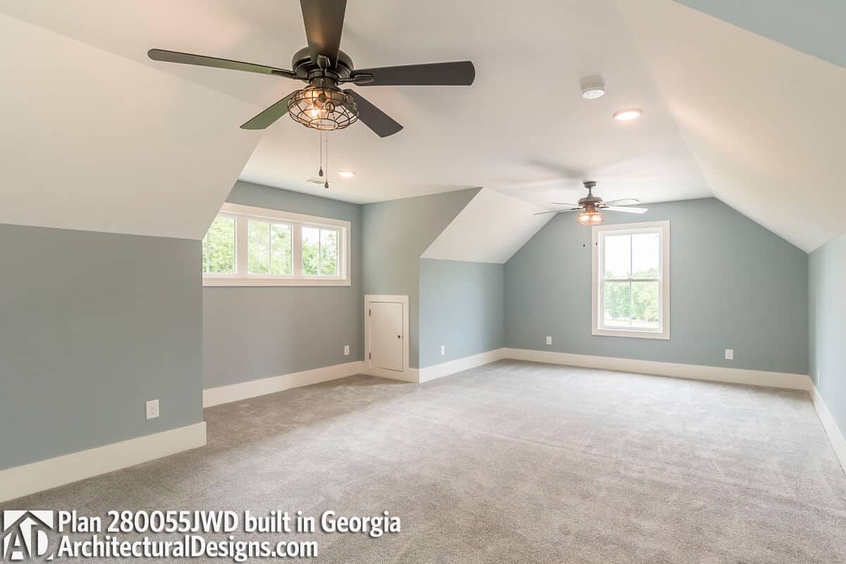 Bonus room with a carpeted floor and a vaulted ceiling mounted with industrial fans.