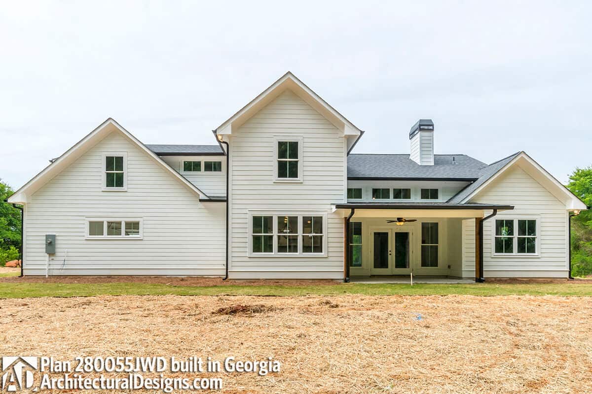 Rear exterior view showcasing the covered porch and a multitude of windows that flood the interior with ample natural light.