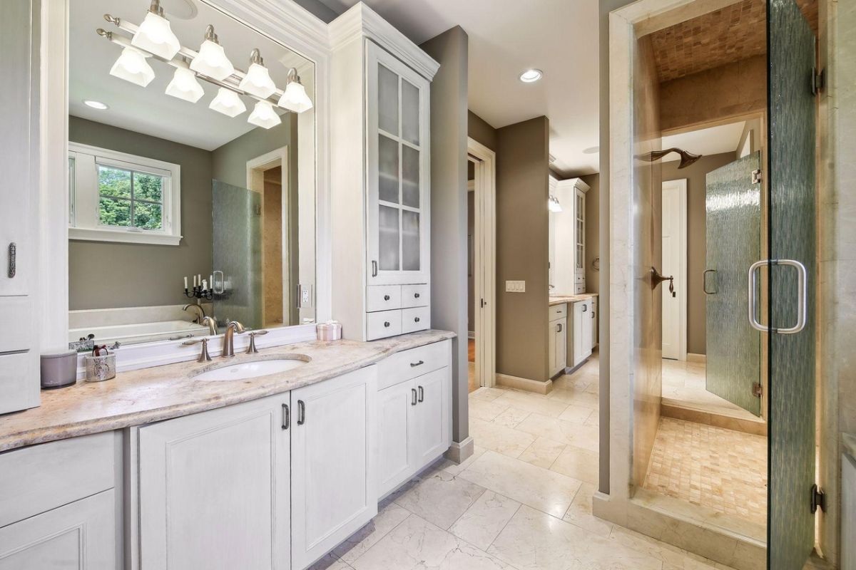 Bathroom with sink, shower and tile flooring.