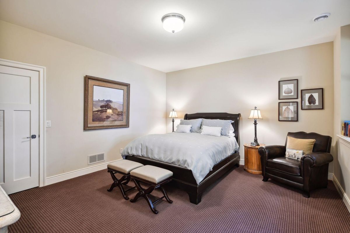 Bedroom with carpet flooring, a couch, and a large bed.