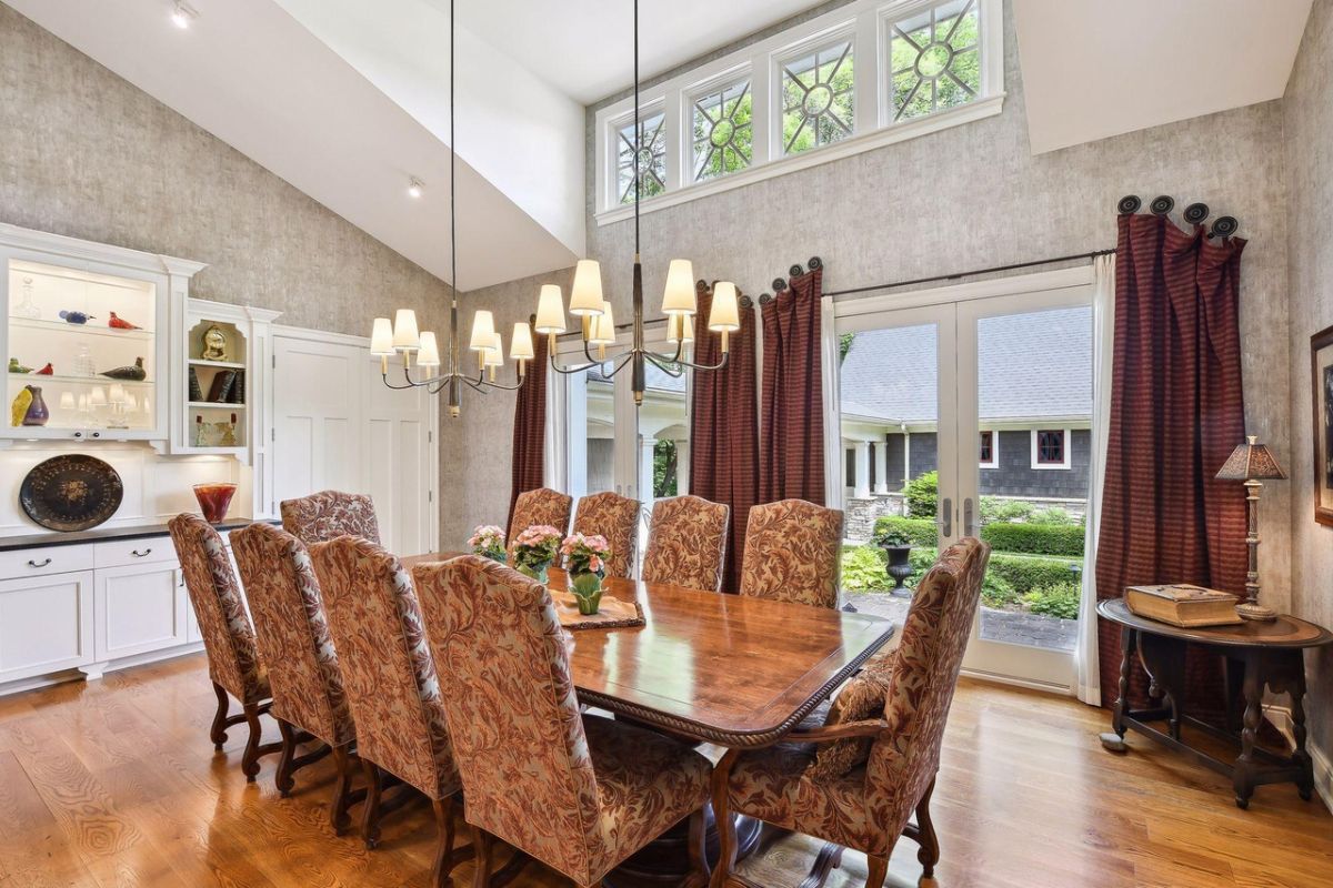 Dining room with custom lighting, wood flooring and a large wooden table.