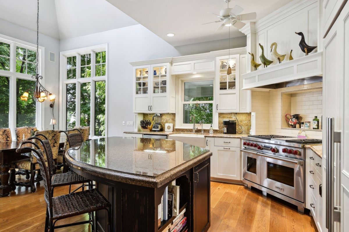 Kitchen with a large island, white cabinets and granite countertops.