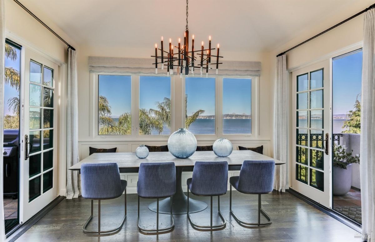 Dining room with a chandelier, glass doors, glass windows and a view of the bay.