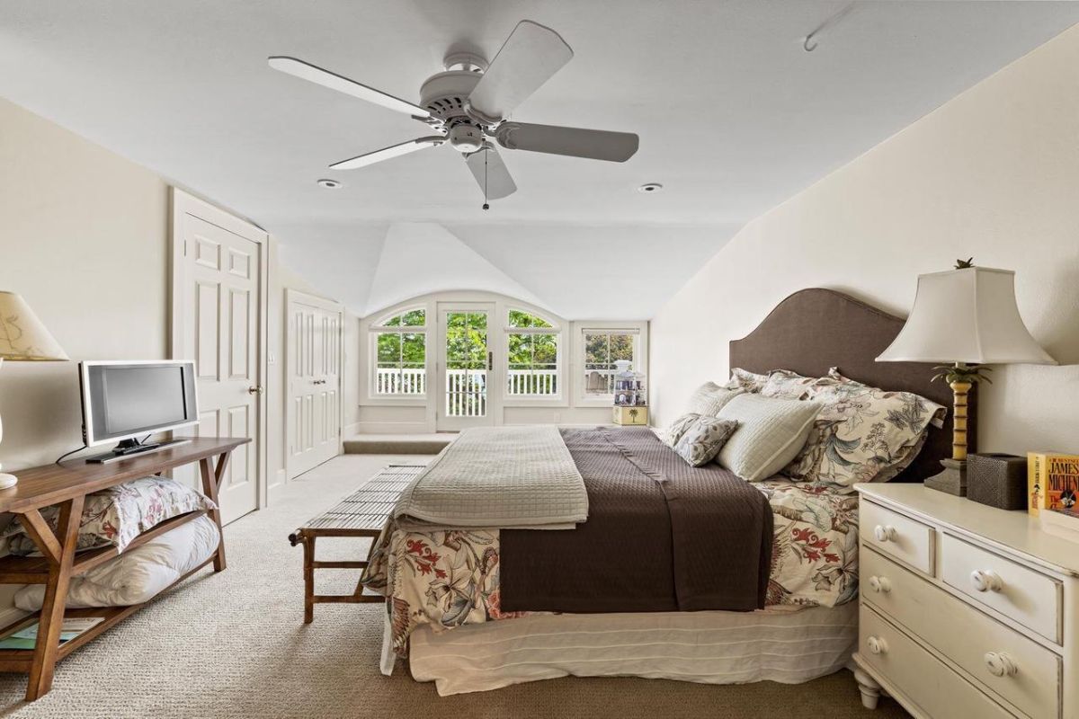 Bedroom with carpet flooring, a ceiling fan, and glass doors.