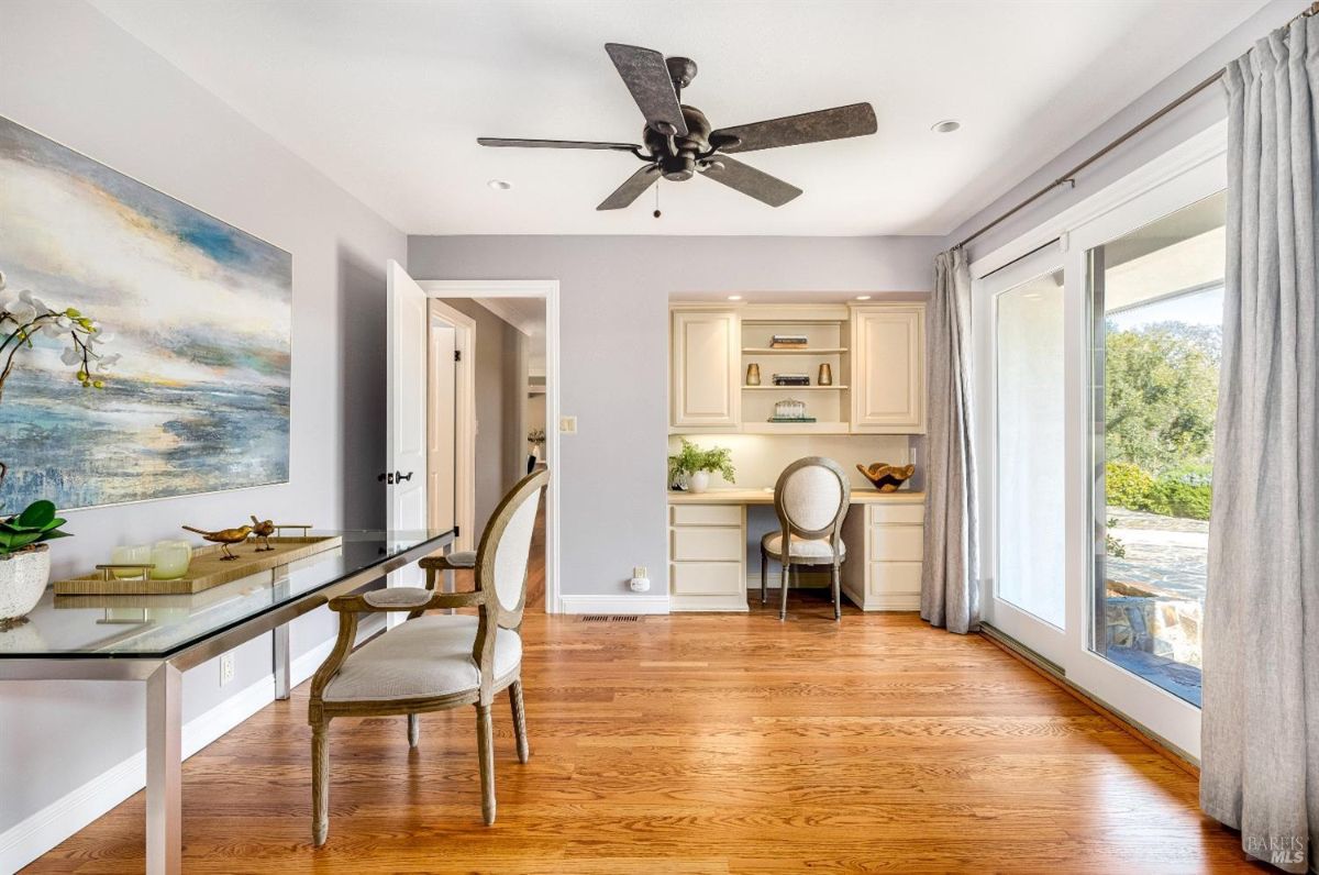 Home office with a ceiling fan, desks and chairs.