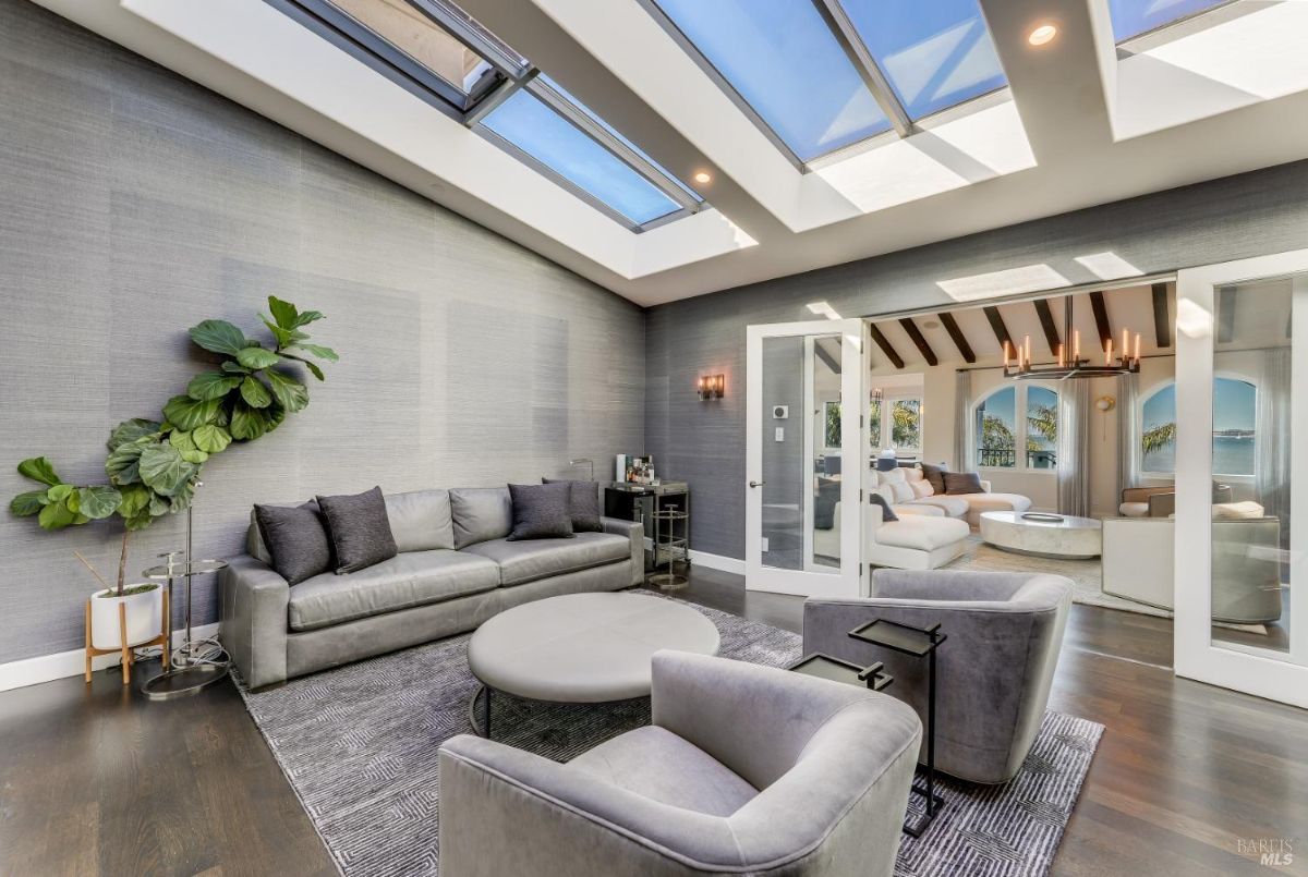 Living room with couches, wooden floors, skylight and custom lights.