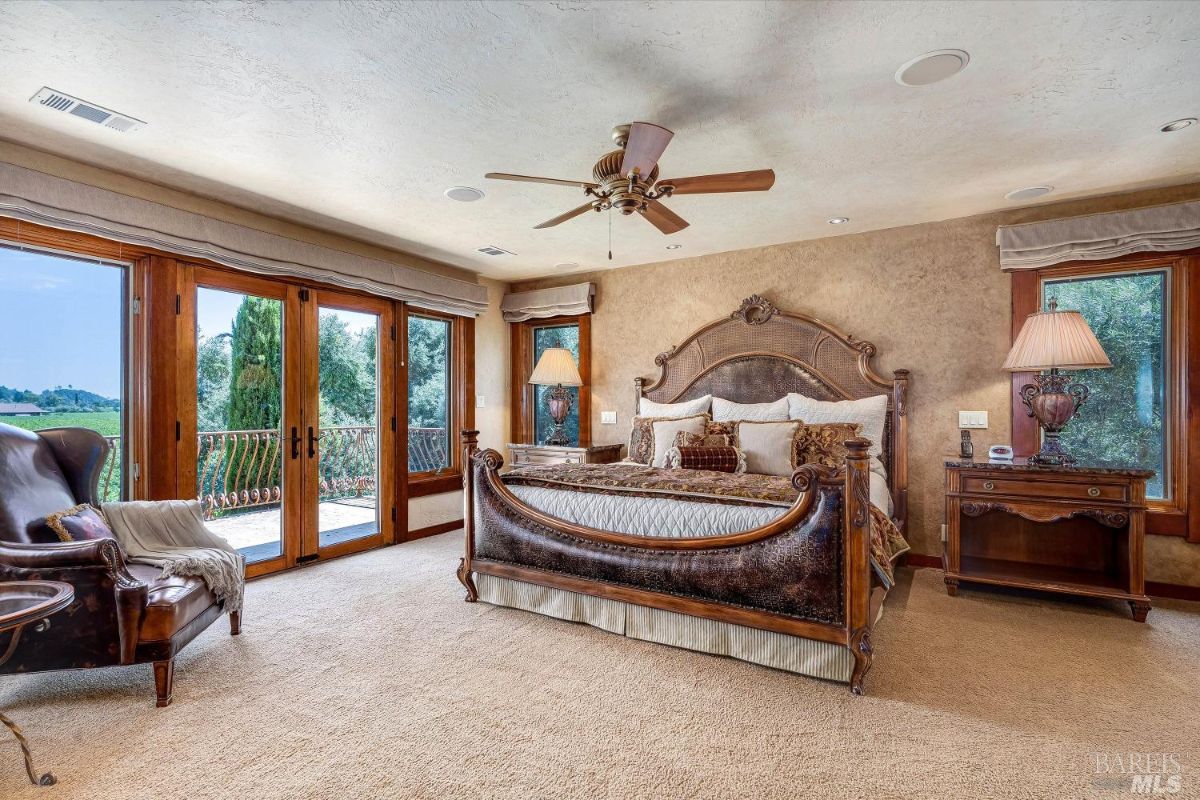 Bedroom with a large bed, glass door, and carpet flooring.