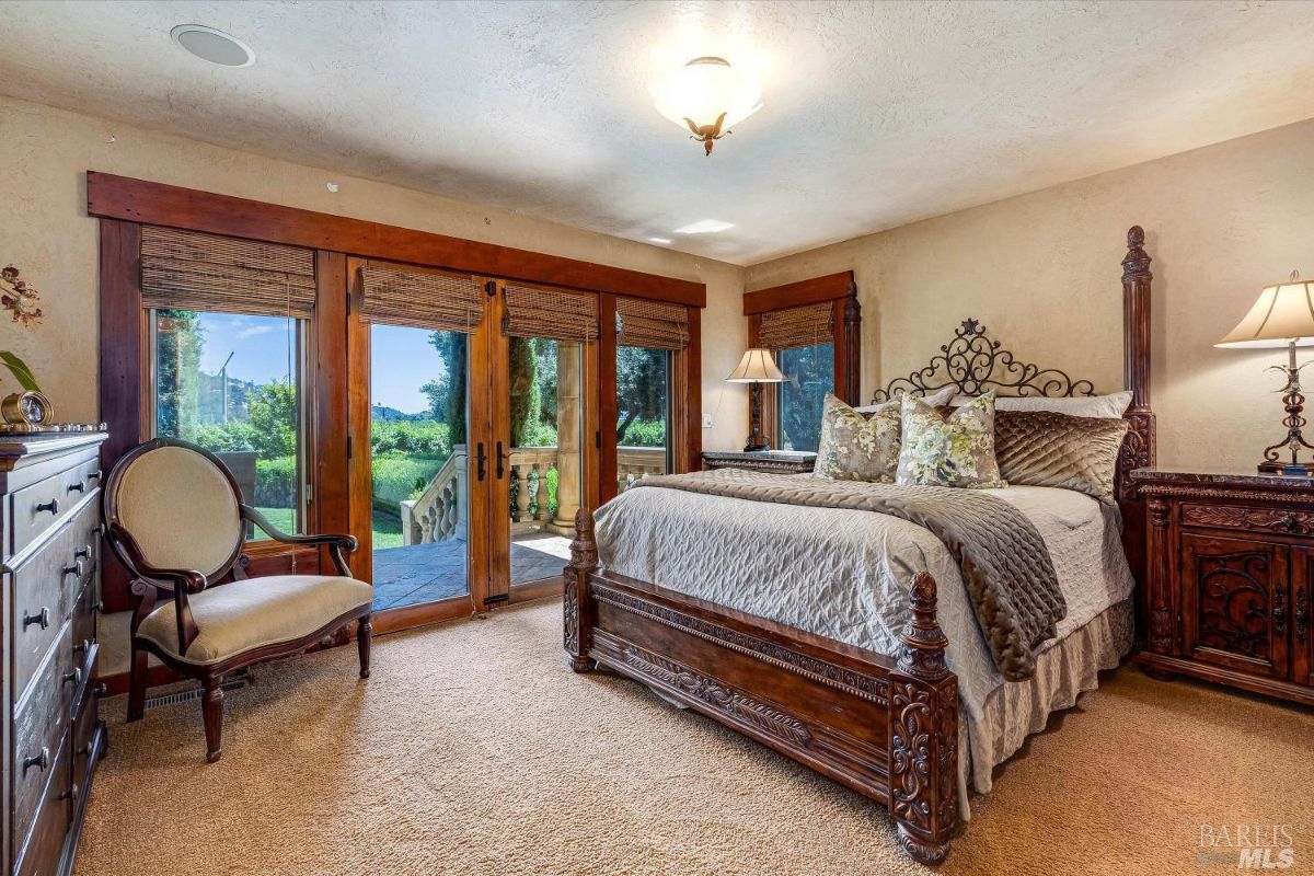 Bedroom with a large bed, glass door, and carpet flooring.