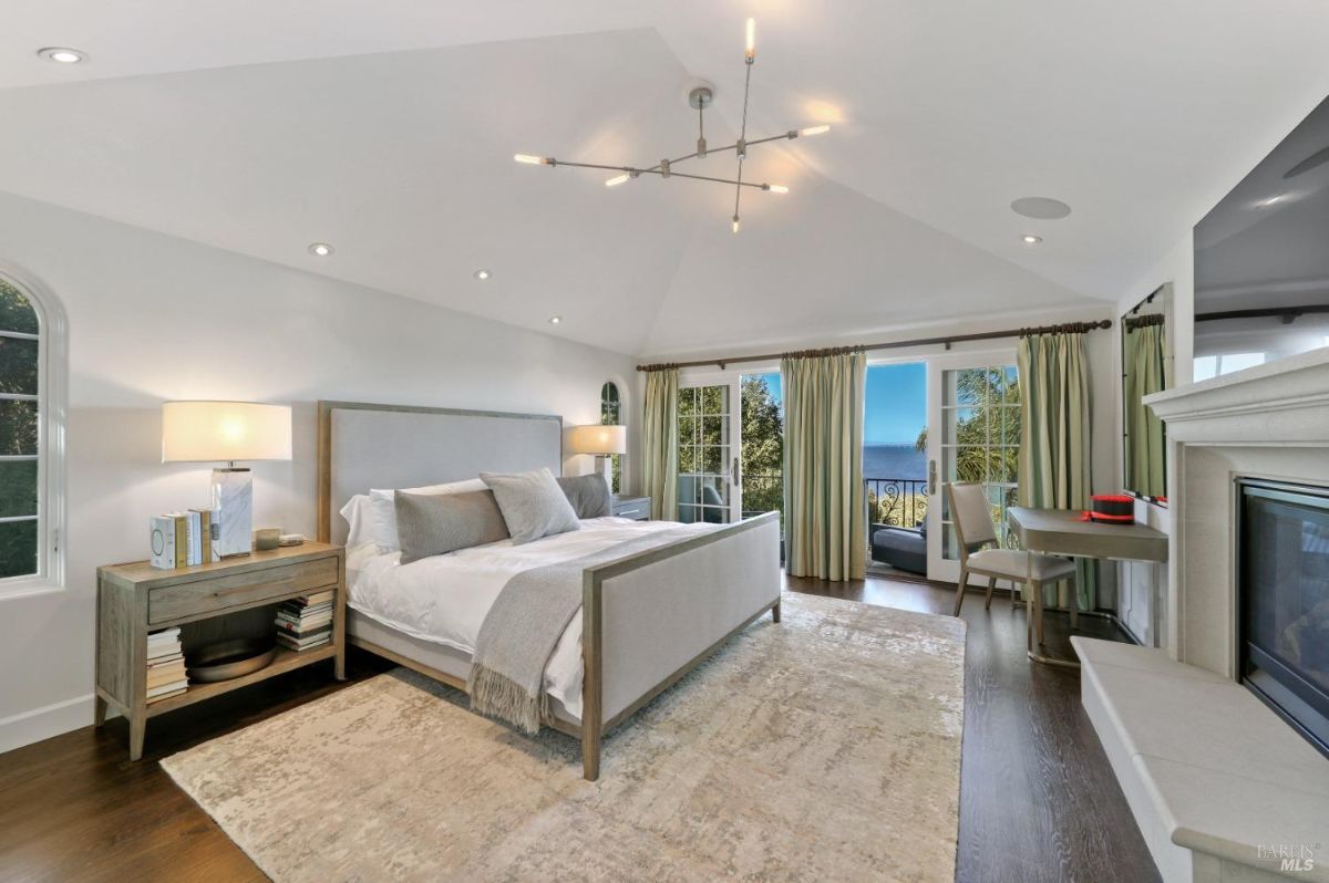 Bedroom with custom lights, a large bed, a TV, and sliding glass doors leading to the balcony.