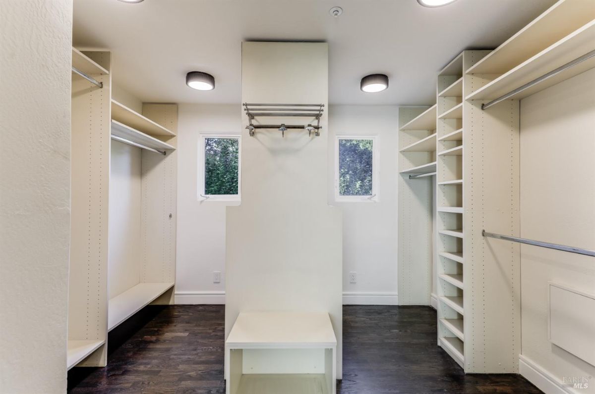 Walk-in closet with white shelves, custom lights and wood flooring.