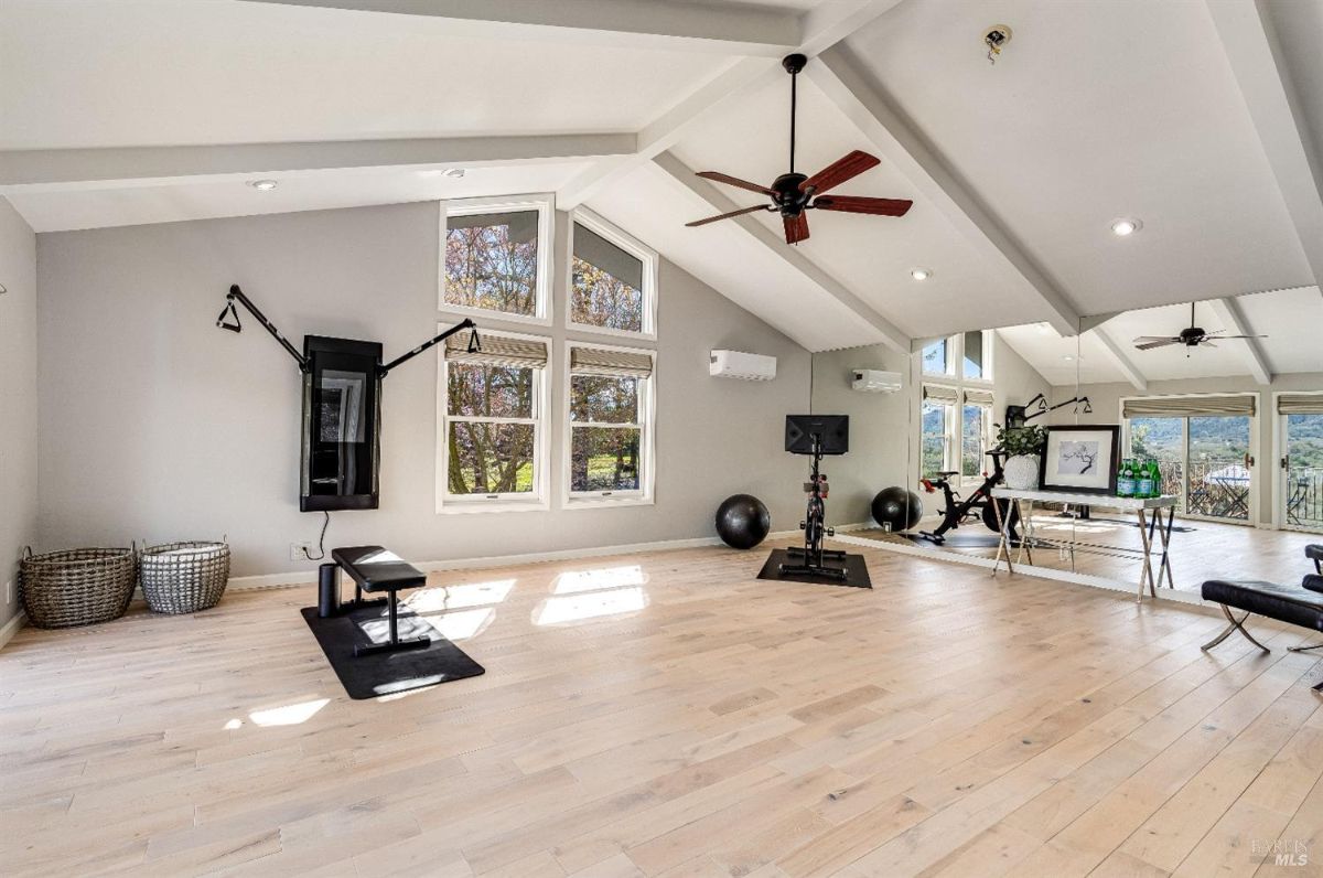 Home gym with a large mirror, Cathedral ceiling and workout equipment.