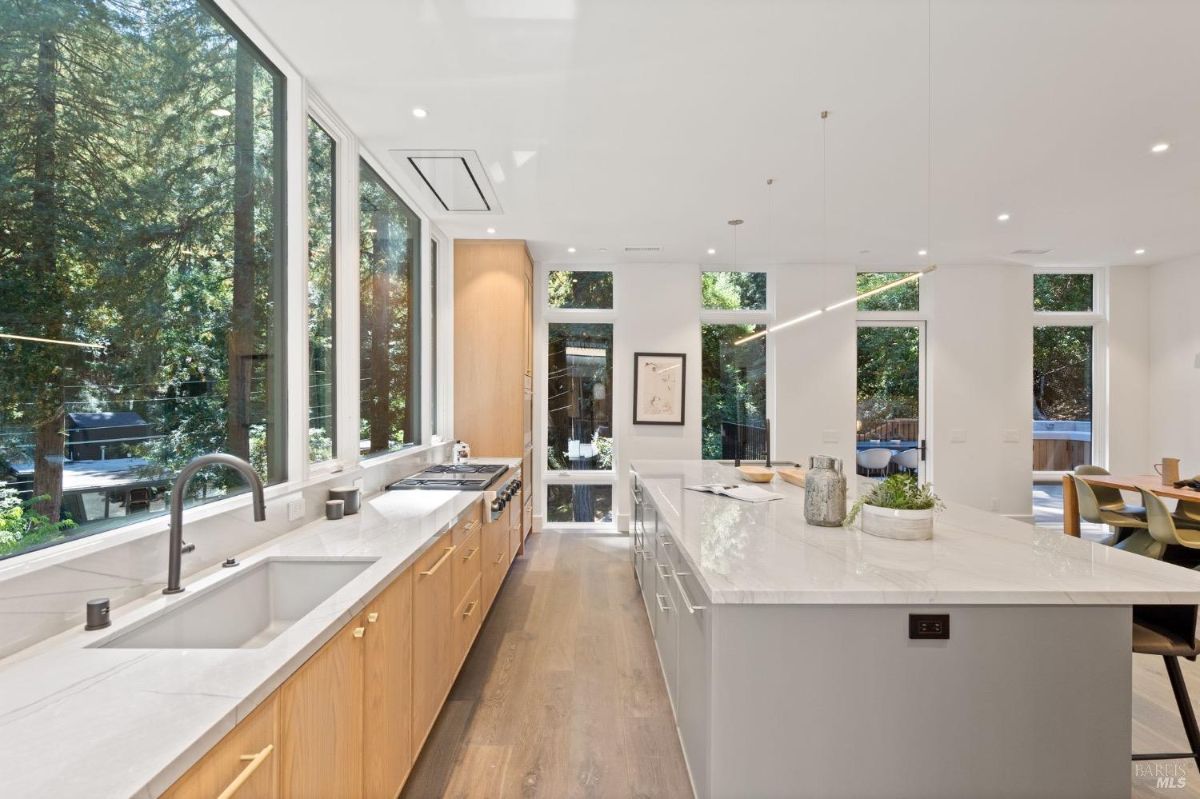 Kitchen with a large island, wood flooring, glass windows and custom lights.