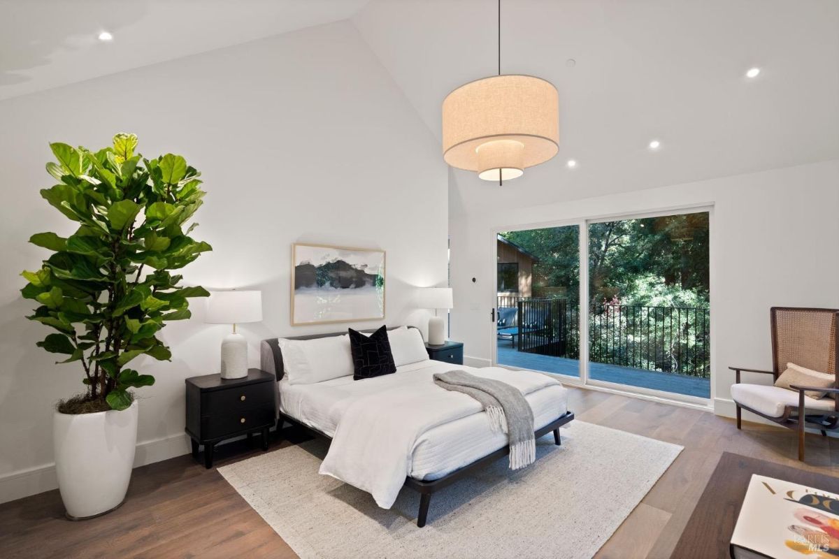 Bedroom with a large bed, custom lights and sliding glass doors.