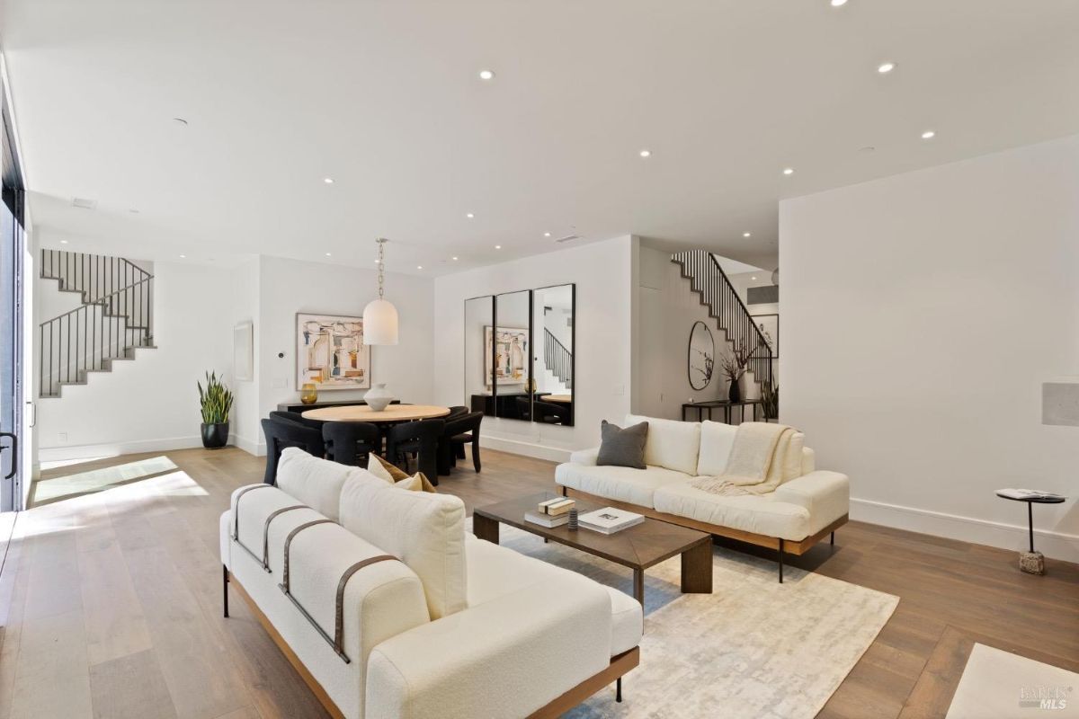 Living room with couches and wood flooring.