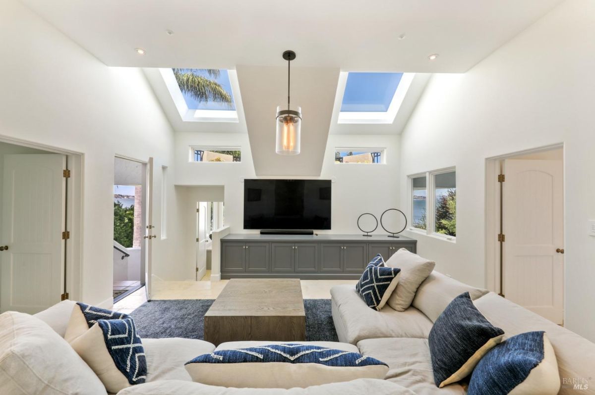 Living room with couches, skylight and a large TV.