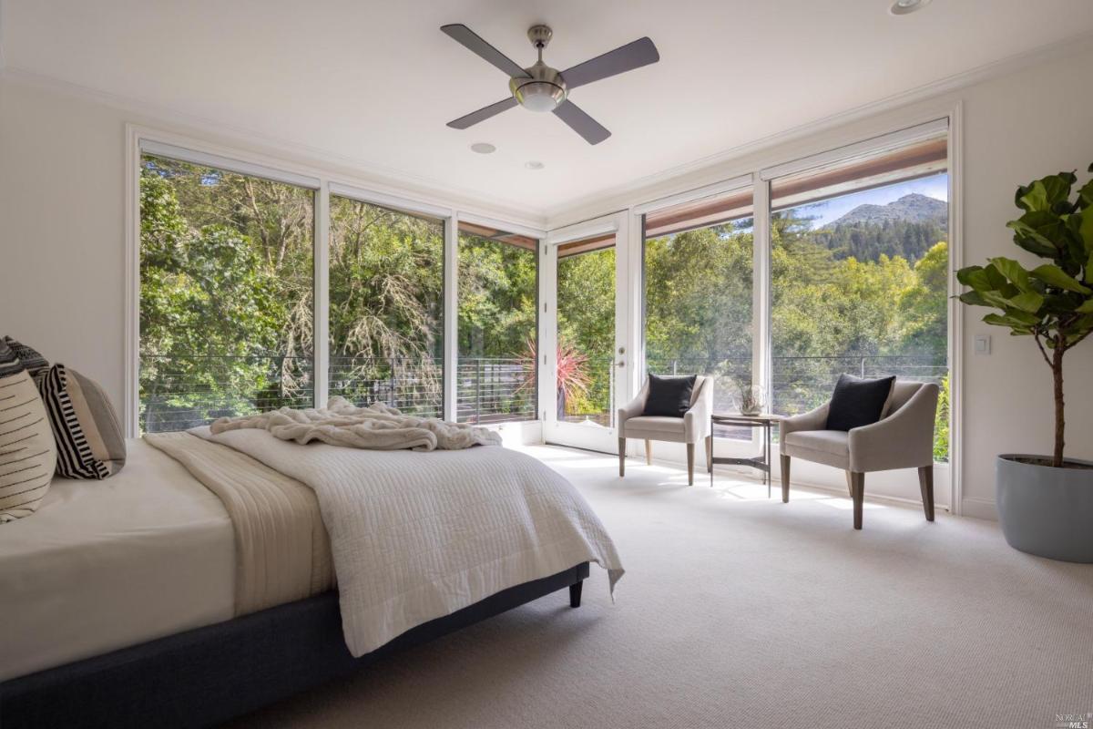 Bedroom with carpet flooring and large glass windows.