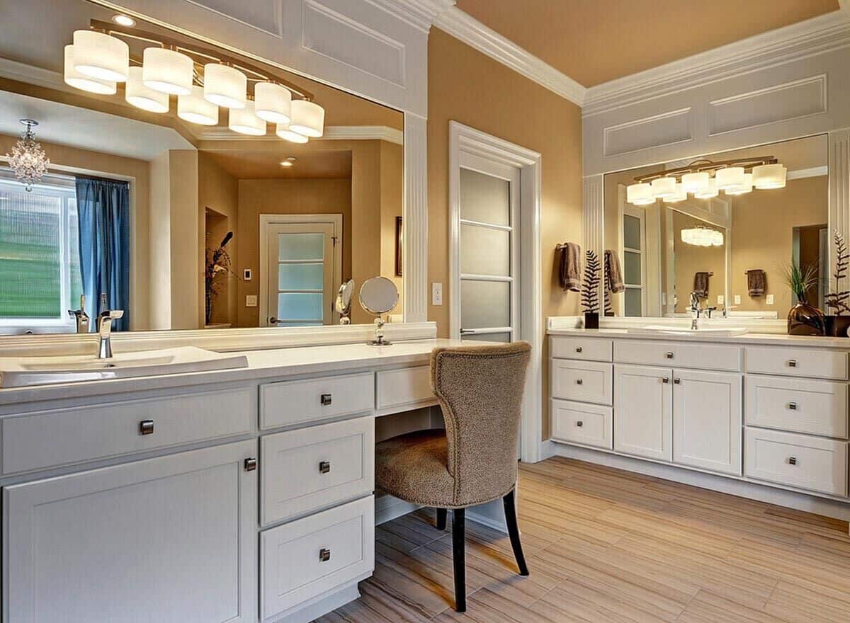 His and her vanities with white cabinets, large mirrors, and a makeup counter.