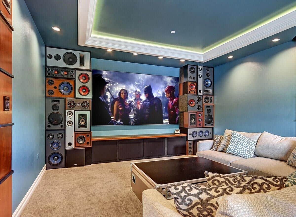 Media room with blue walls, carpeted floor, and a tray ceiling highlighted by coved lighting.