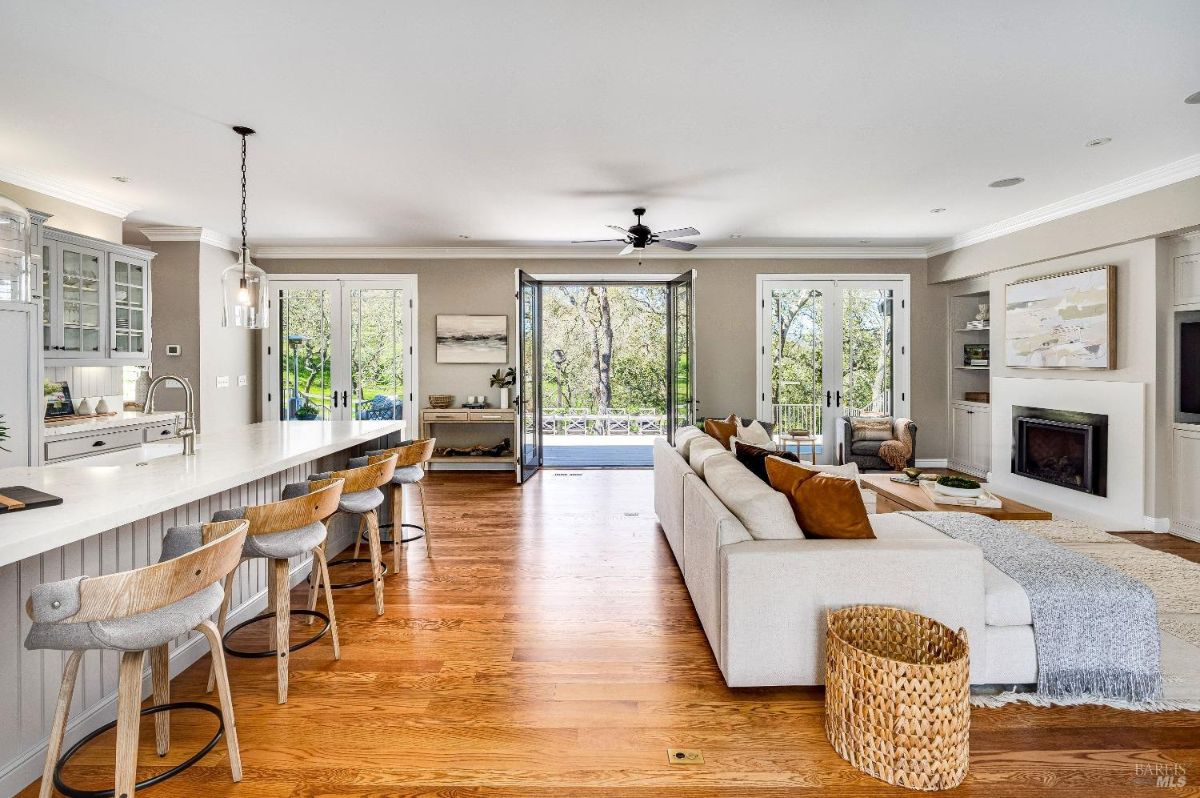 Living room with couches, wood flooring, ceiling fan, and a fireplace.