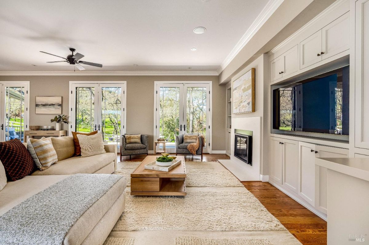 Living room with couches, wood flooring, ceiling fan, and a fireplace.