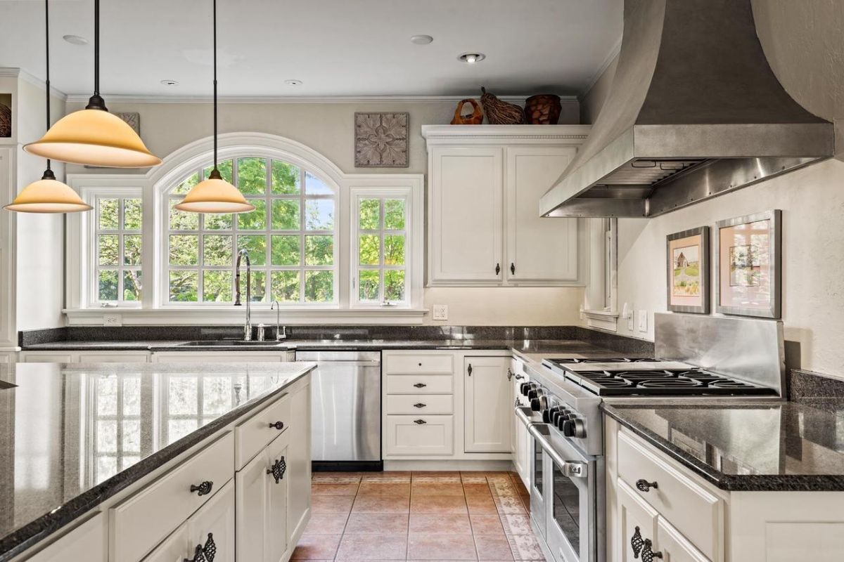 Kitchen with white cabinets and marble counter tops.