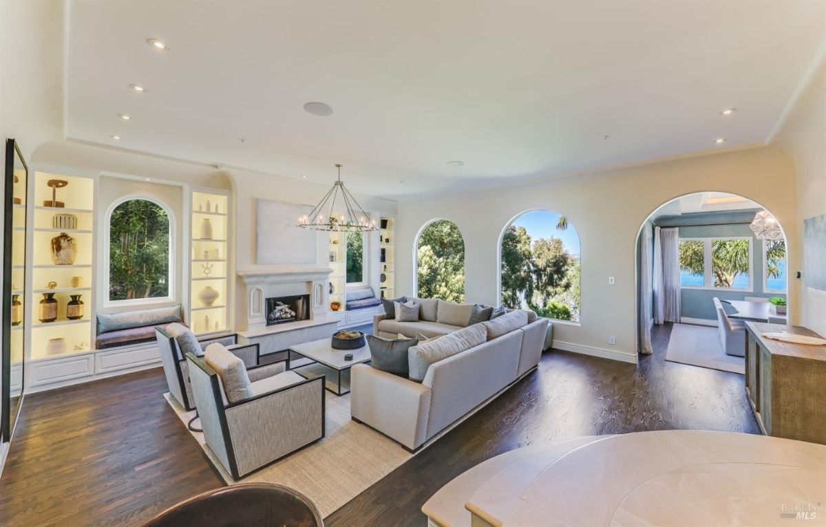 Living room with a chandelier, couches, wooden floors, and a fireplace.