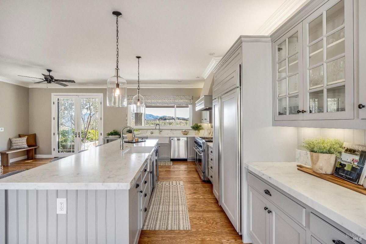 Kitchen with white cabinets, custom lights, and a large island.