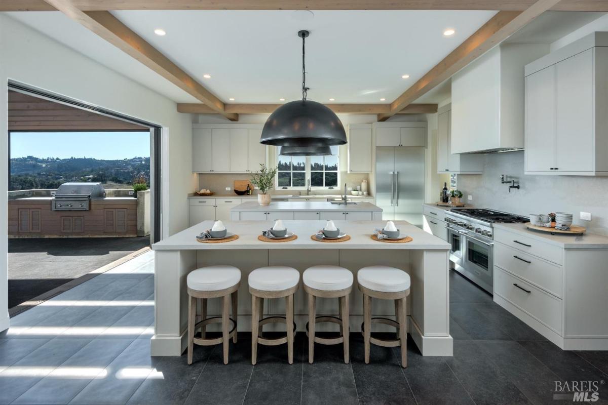 Kitchen with open beam ceiling and custom lights.