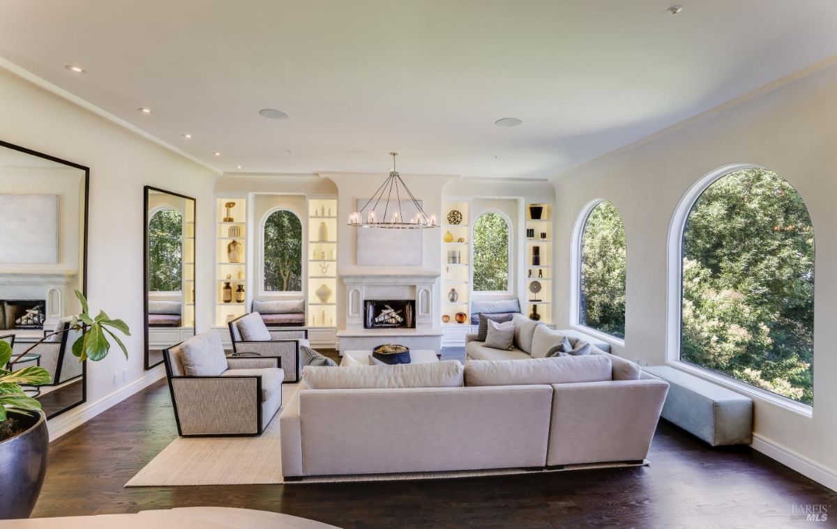 Living room with a chandelier, custom lights, couches, wooden floors, and a fireplace.