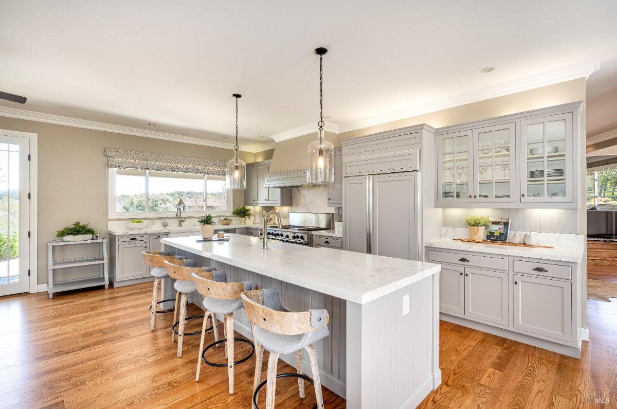 Kitchen with white cabinets, stainless steel appliance, custom lights, and a large island.