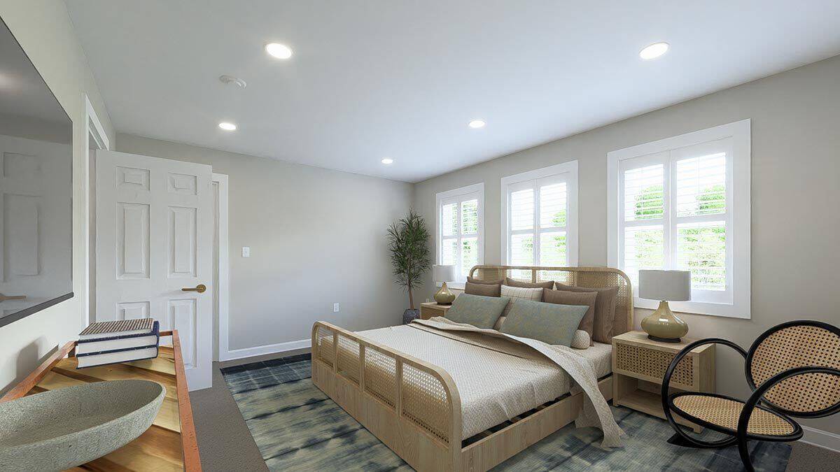 Primary bedroom with a rattan bed, matching nightstands, and a round chair over the blue area rug.