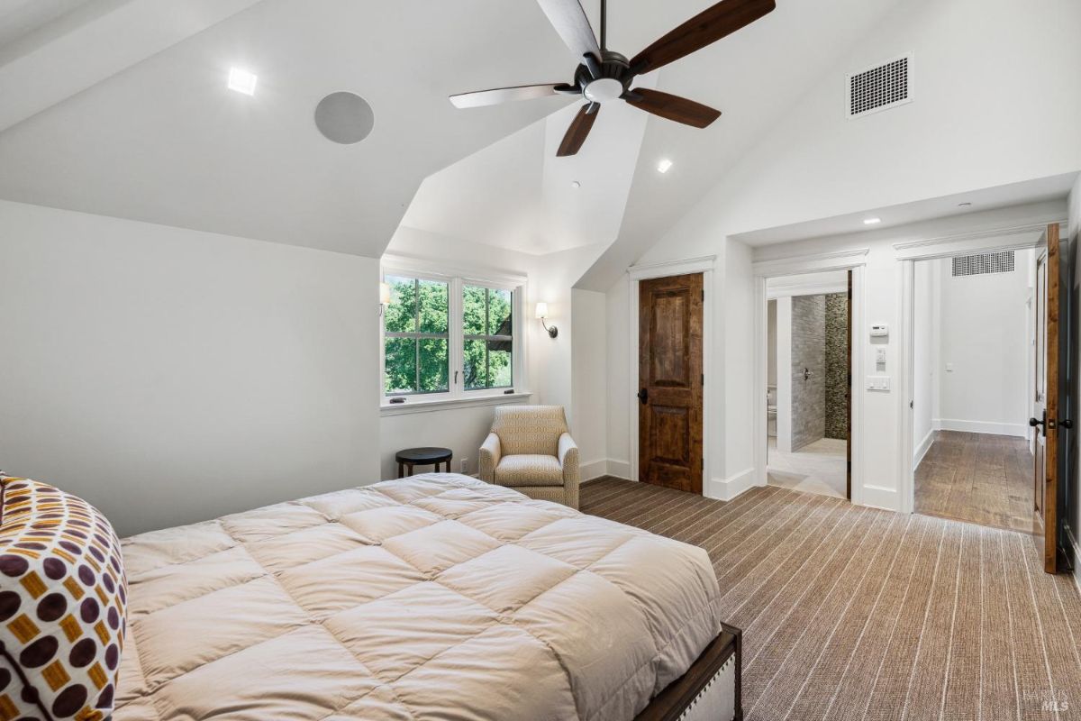 Bedroom with a large bed, bathroom and glass windows.