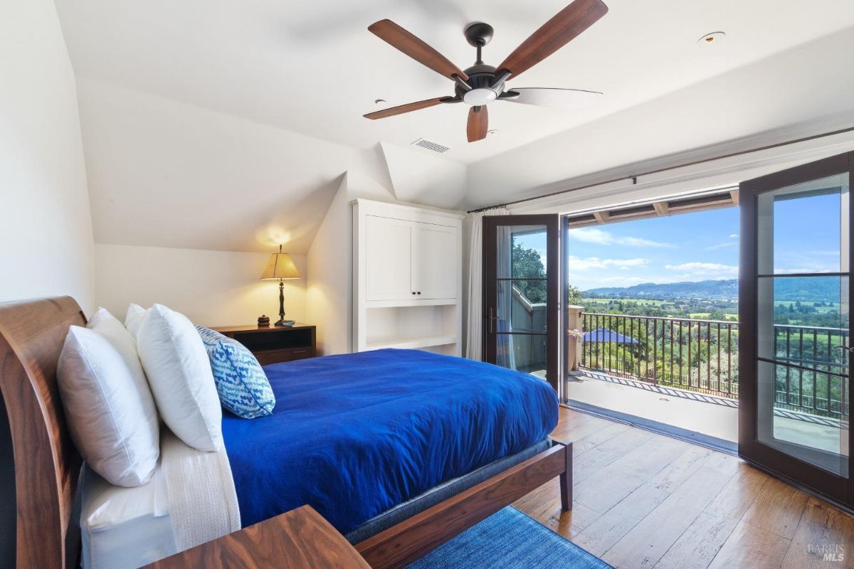 Bedroom with a large bed, glass doors and a balcony.