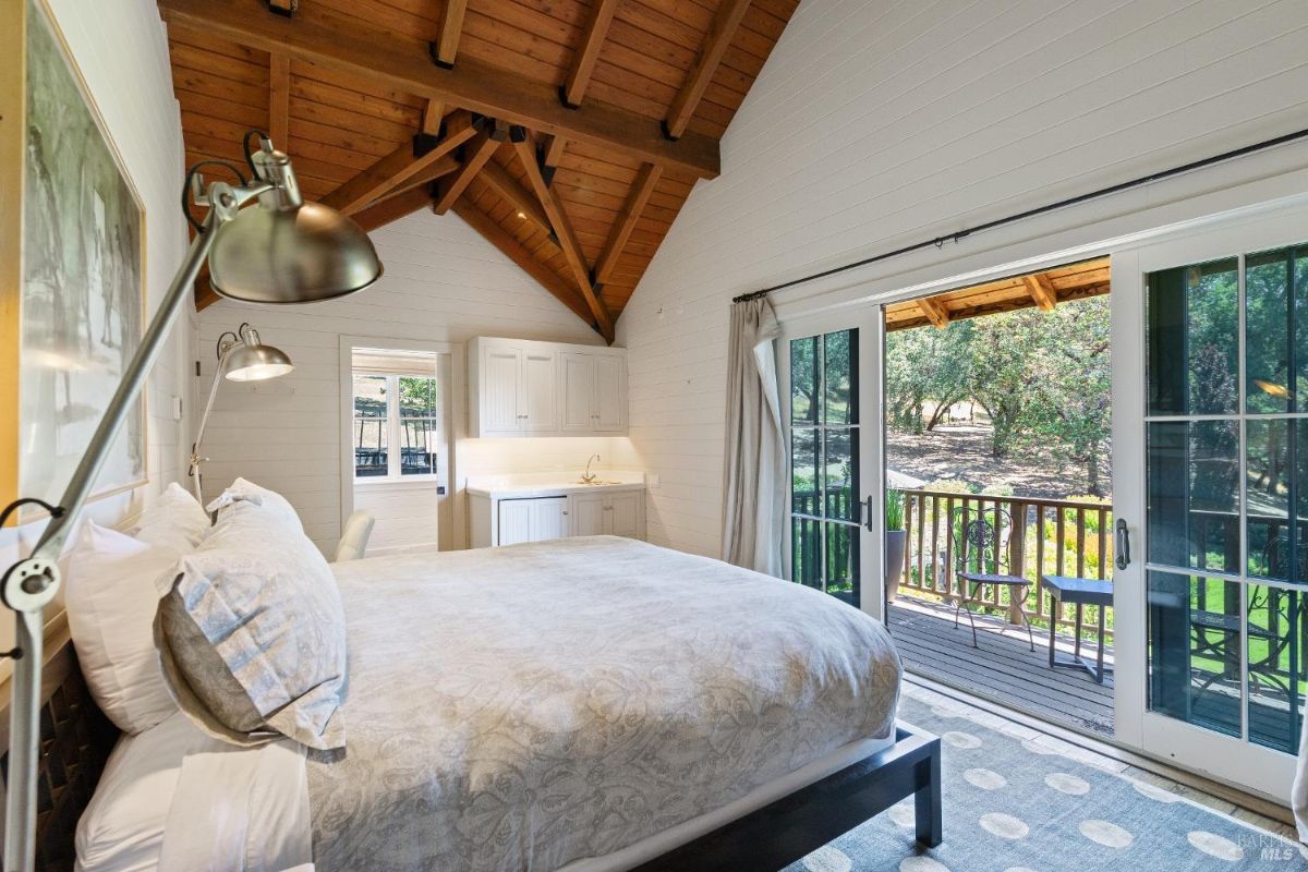 Bedroom with a large bed, glass doors and a balcony.