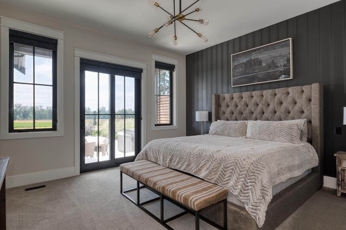 Primary bedroom with a tufted bed, a striped bench, and outdoor access.