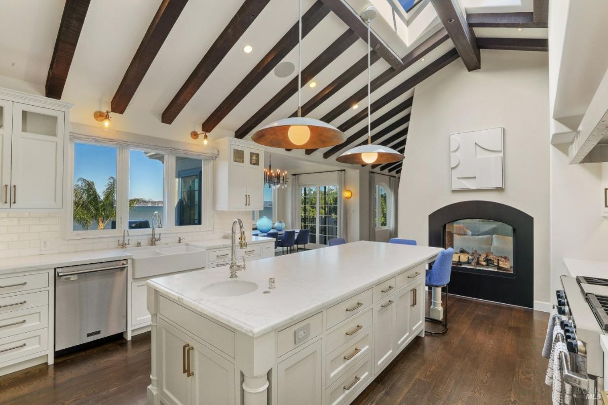 Kitchen with a large island w/sink, marble countertops, skylight and custom cabinets.