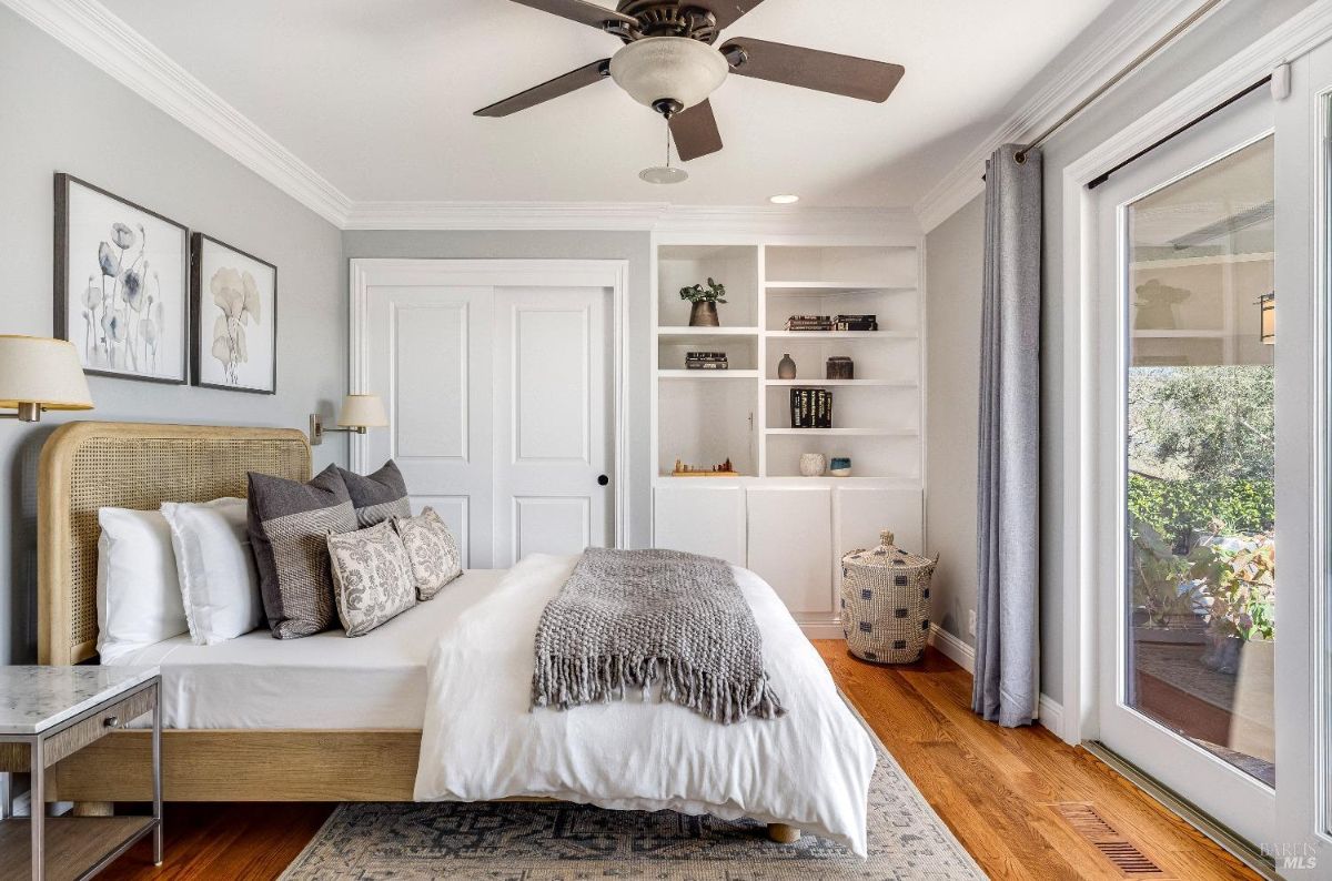 Bedroom with a ceiling fan, wooden floors, a large bed, and sliding glass doors.