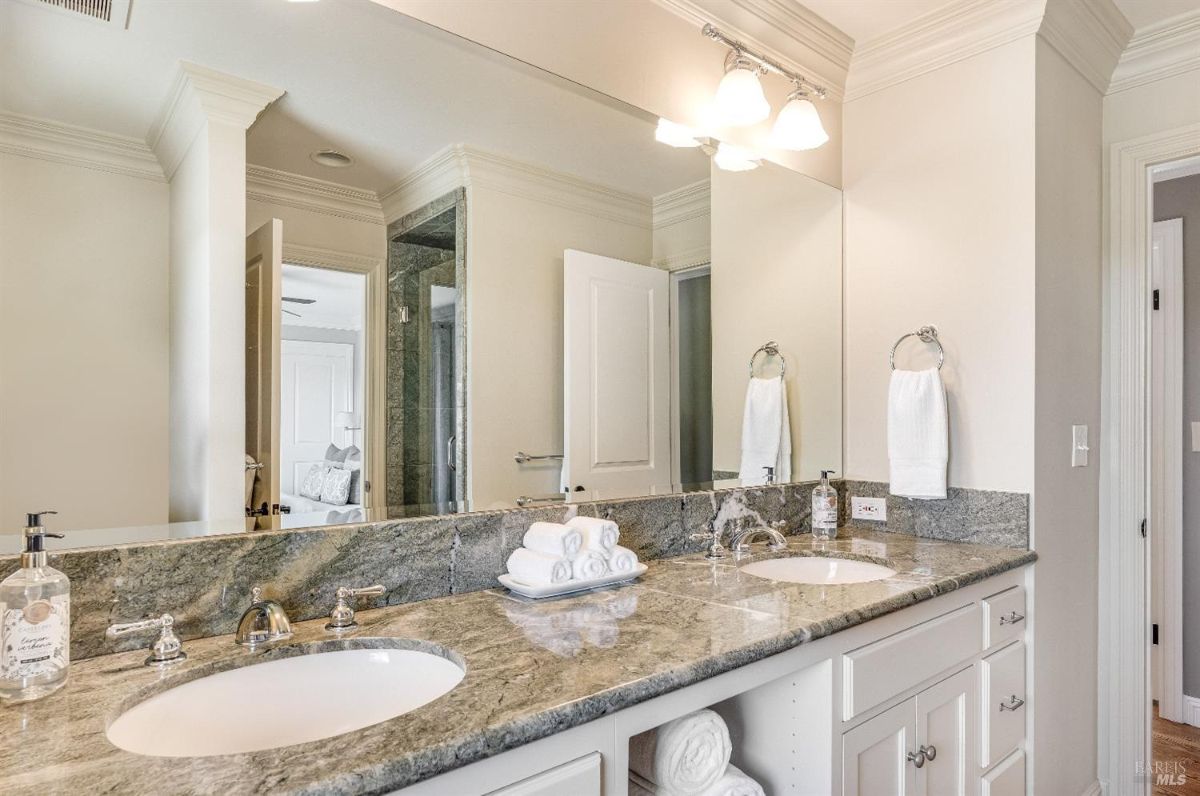 Bathroom with dual sinks, a large mirror and custom lights.