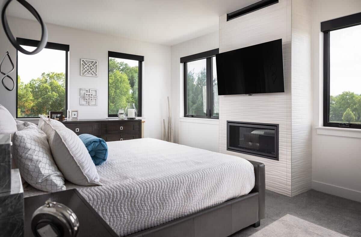 Primary bedroom with an upholstered bed and a fireplace topped with a TV.