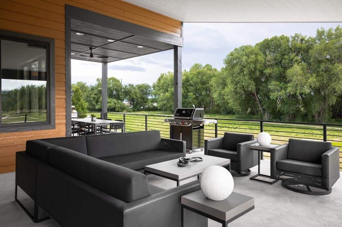 Covered deck with outdoor dining, a barbecue grill, and leather seats surrounding the metal coffee table.