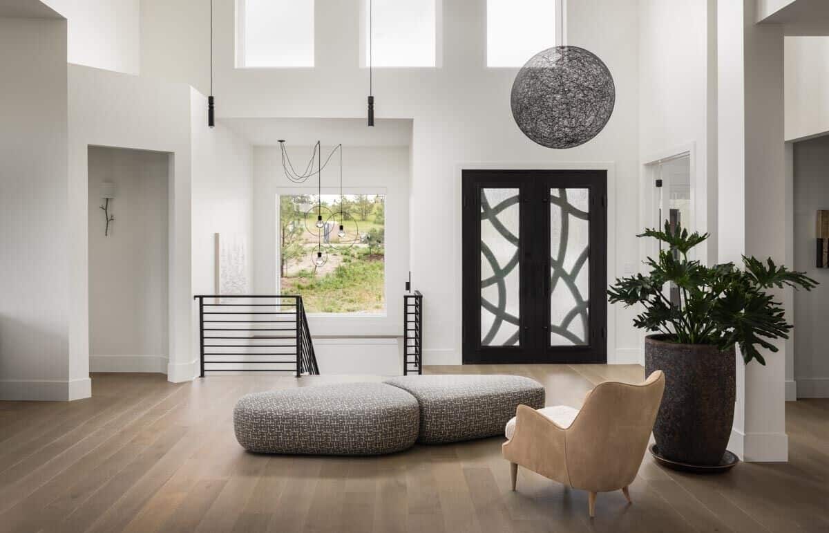 Foyer with a French front door, modern seats, and a spherical pendant hanging from the tall ceiling.