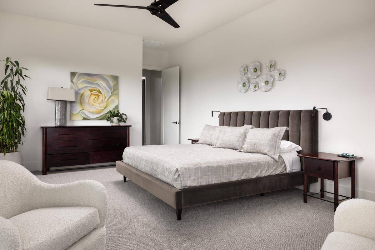 The primary bedroom includes an upholstered bed and a dark wood dresser topped with a table lamp and a painting.