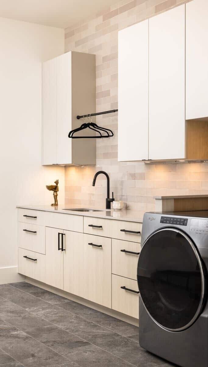 Laundry room with white cabinets, a sink, and slate flooring.