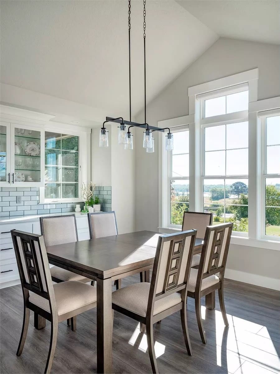 Dining room with vaulted ceiling and a wooden dining set that blends in with the hardwood floor.