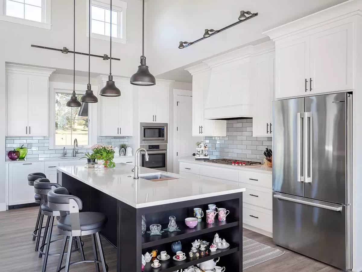 Kitchen with white cabinetry, stainless steel appliances, and a breakfast island lined with round bar stools.