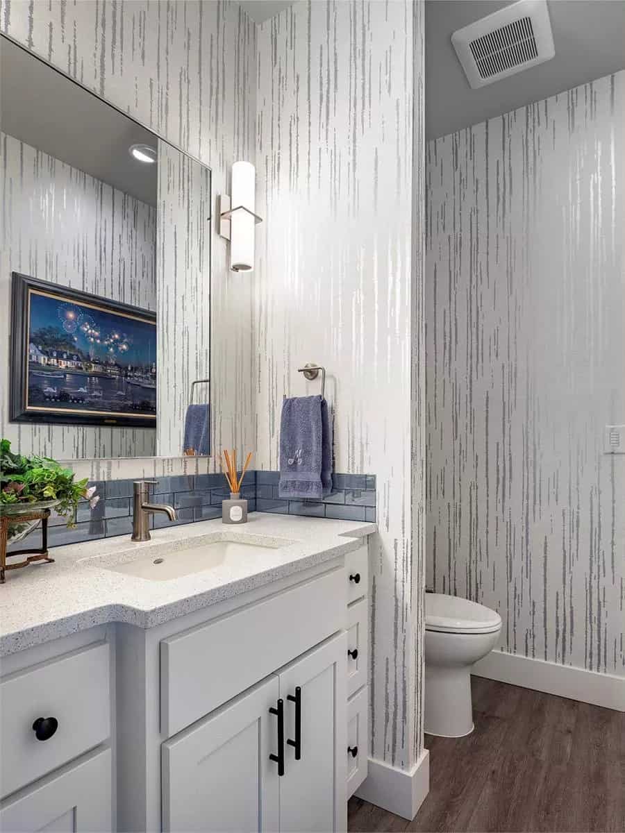 Powder room with a toilet area and a sink vanity paired with a large mirror.